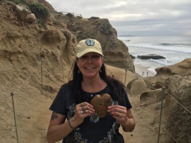 A woman holding something on top of the beach.