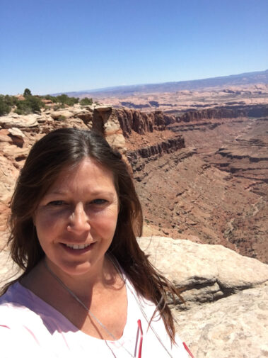 A woman standing on top of a mountain near the desert.