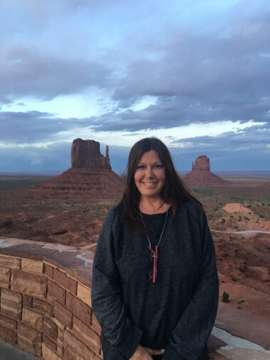 A woman standing in front of the monument valley.