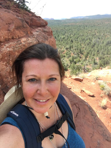 A woman taking a selfie on top of a mountain.
