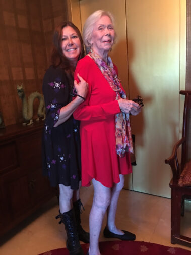 A woman standing next to an older lady.