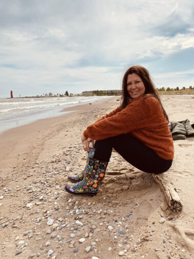 A woman sitting on the beach wearing boots