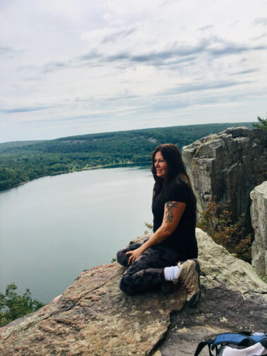 A woman sitting on top of a rock near the water.